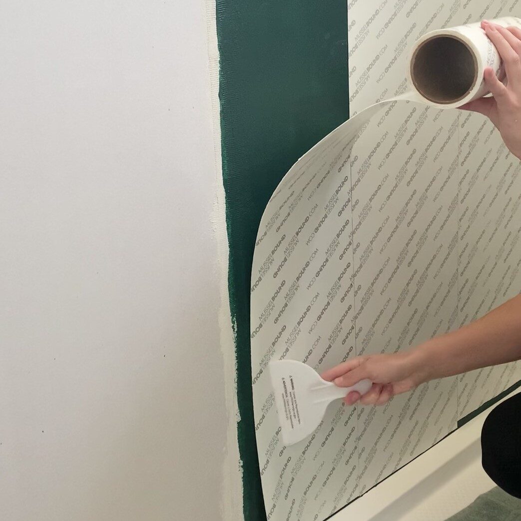 woman applying Musselbound to shower wall