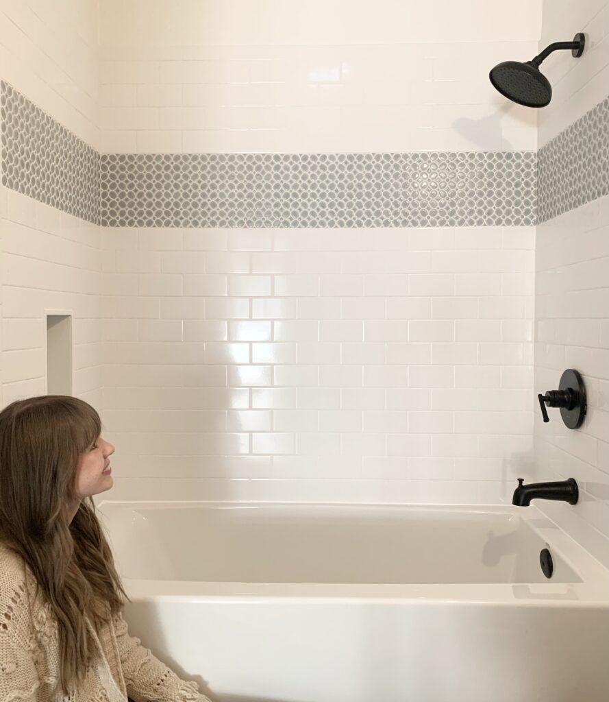 DIY shower with white subway tile and blue flower mosaic tile and black shower fixtures and hardware