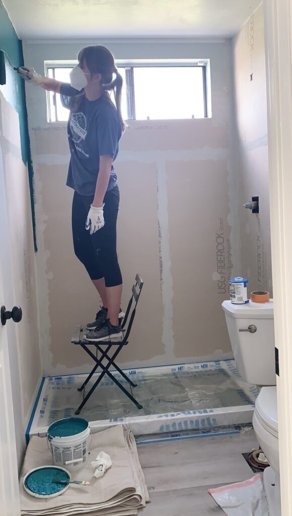 woman waterproofing shower wall with Mapei AquaDefense