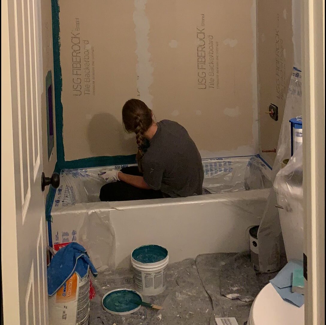 woman using Mapei AquaDefense on DIY shower remodel
