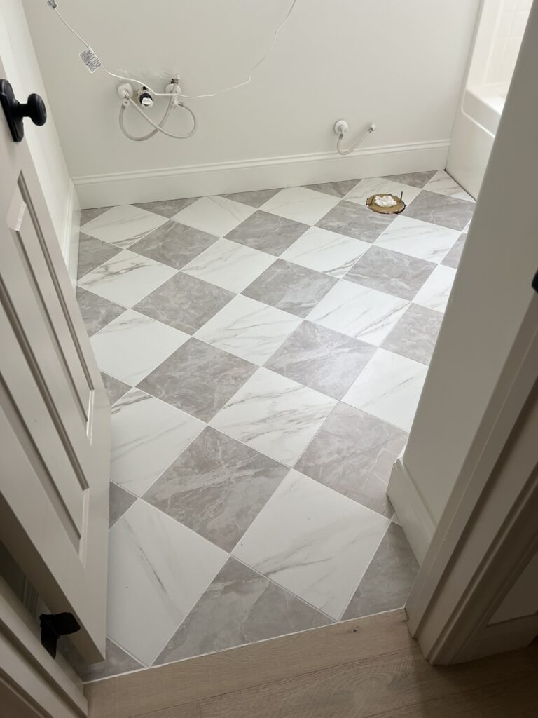 checkered tile flooring with white grout and white baseboards
