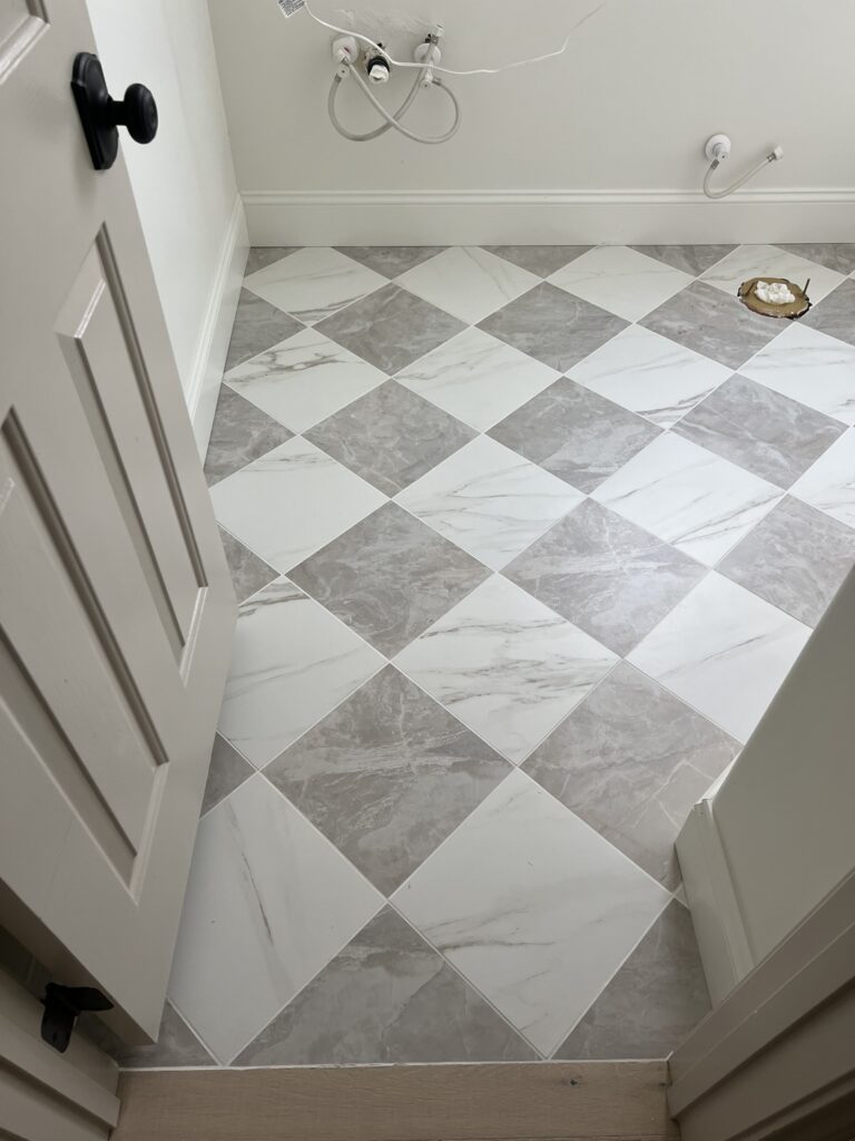 checkered floor in bathroom with white baseboards and white walls