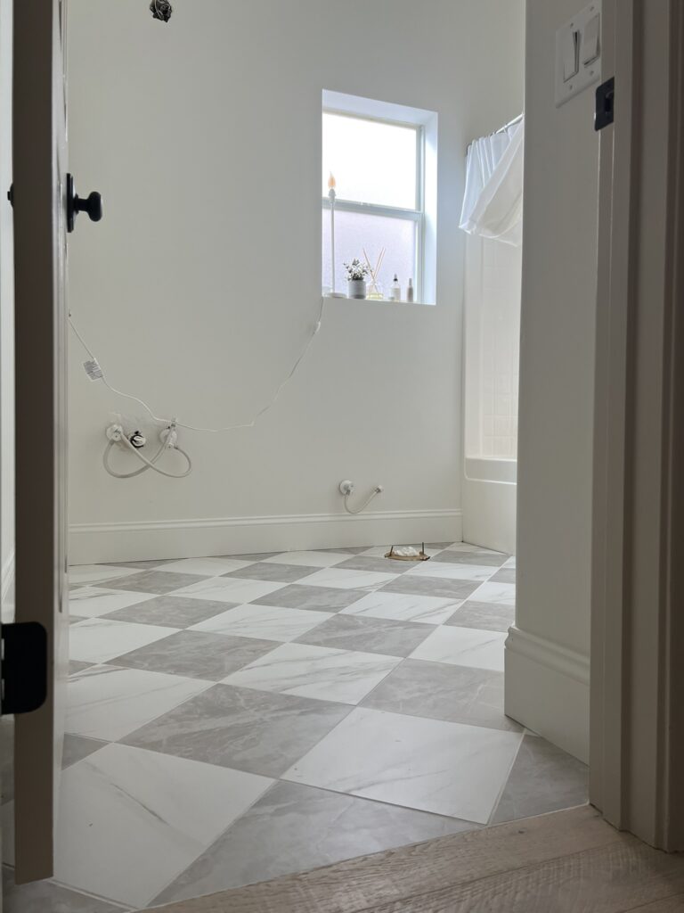 checkered floor in bathroom with white baseboards and white walls