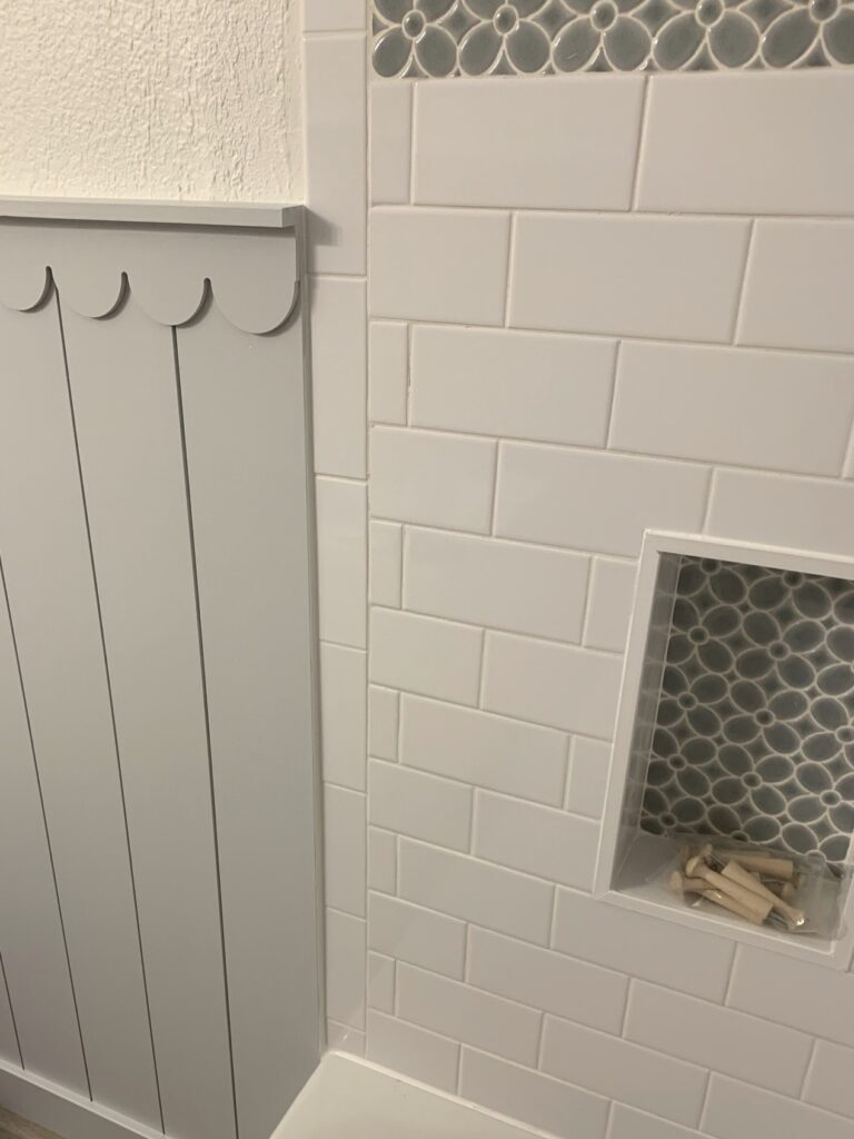 shower niche with mosaic flower tile in white subway tile shower