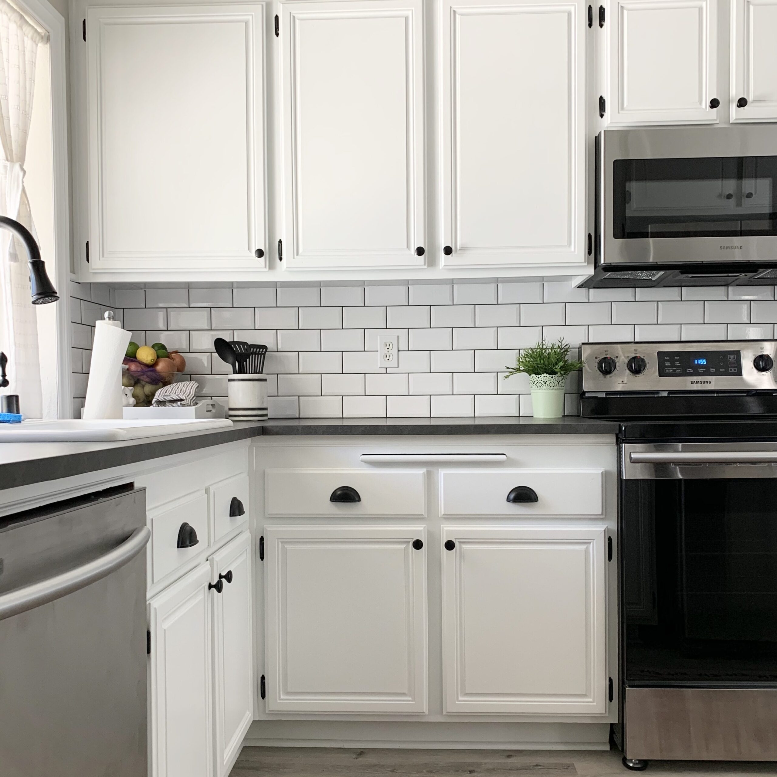 Pure White kitchen cabinets with black overlay hinges, knobs and cup pulls