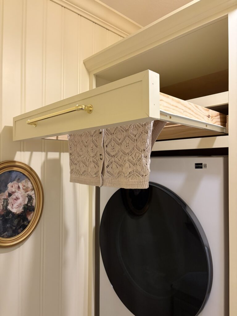 diy drying rack for clothes above the washer and dryer in a butter yellow laundry room